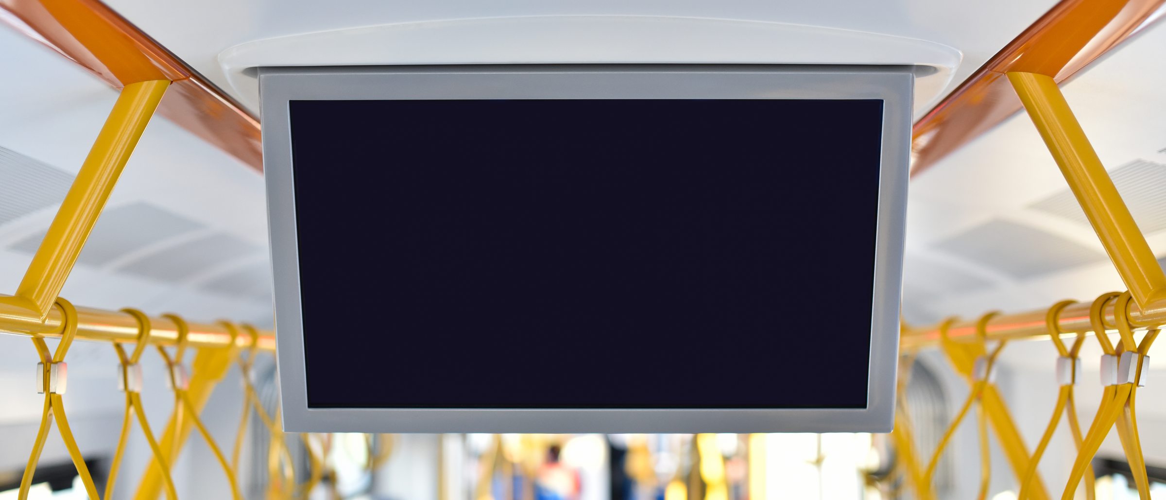 Innenraum eines Linienbusses mit gelben Haltegriffen, Fahrgäste unscharf im Hintergrund